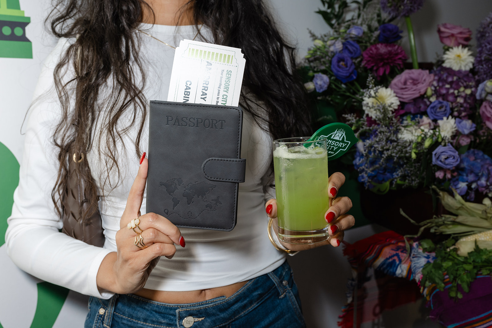 Guest holding a Sensory City passport with boarding passes and a green cocktail